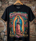 Black t-shirt with Guadalupe design on a hanger against a brick wall background